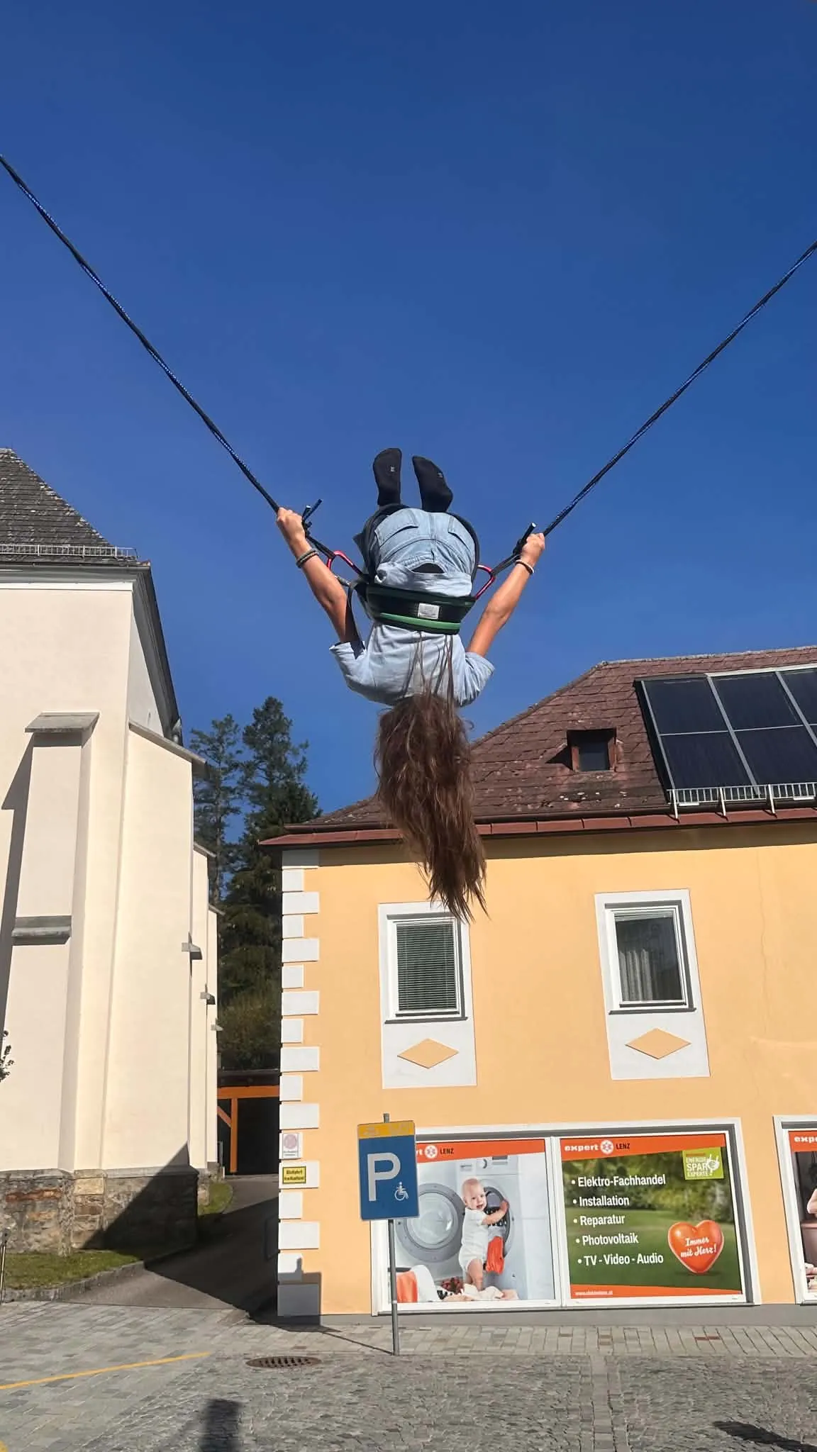Kind dreht sich am Bungee-Trampolin kopfüber in der Luft