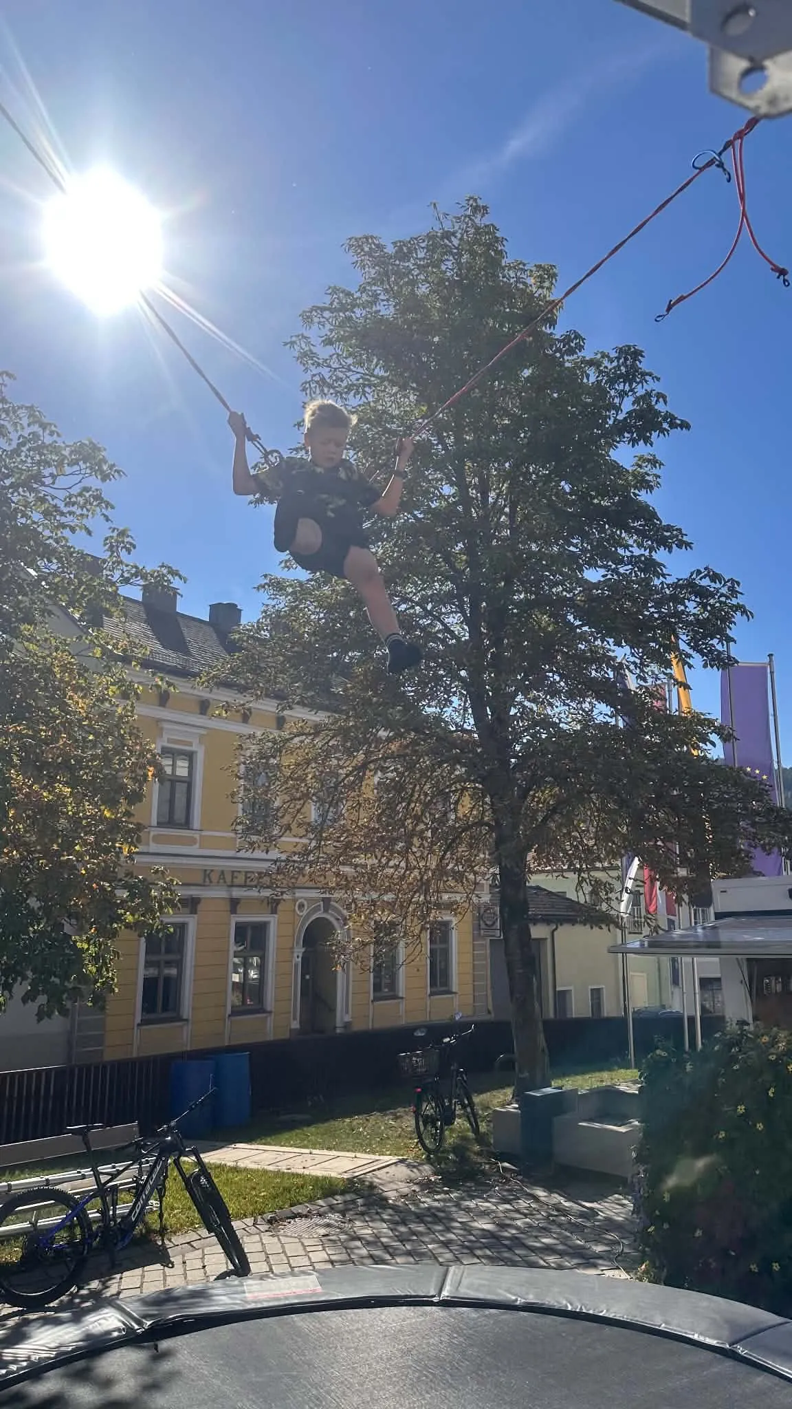 Kind springt am Bungee-Trampolin im Gegenlicht der Sonne